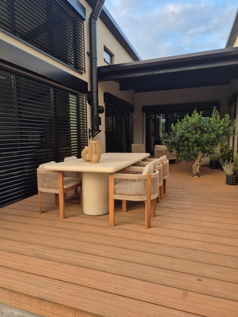 WPC-Terrasse im Abendlicht, die Dielenstruktur läuft diagonal auf den Esstisch zu