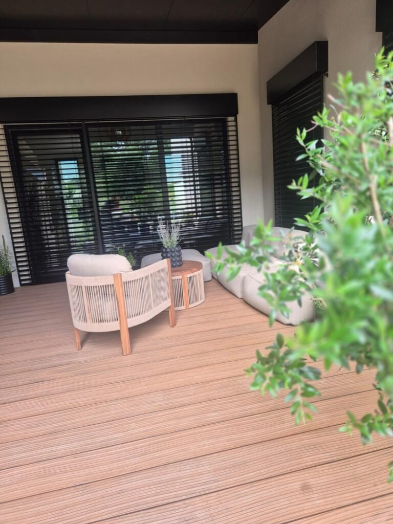 Überdachter Teil der WPC-Terrasse mit zwei Loungesesseln, rundem Beistelltisch und Outdoorsofa